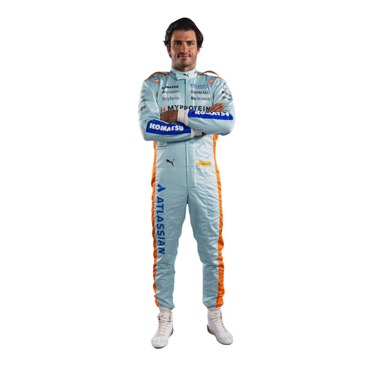 Carlos wearing a light blue racing suit with various sponsor logos on a white background