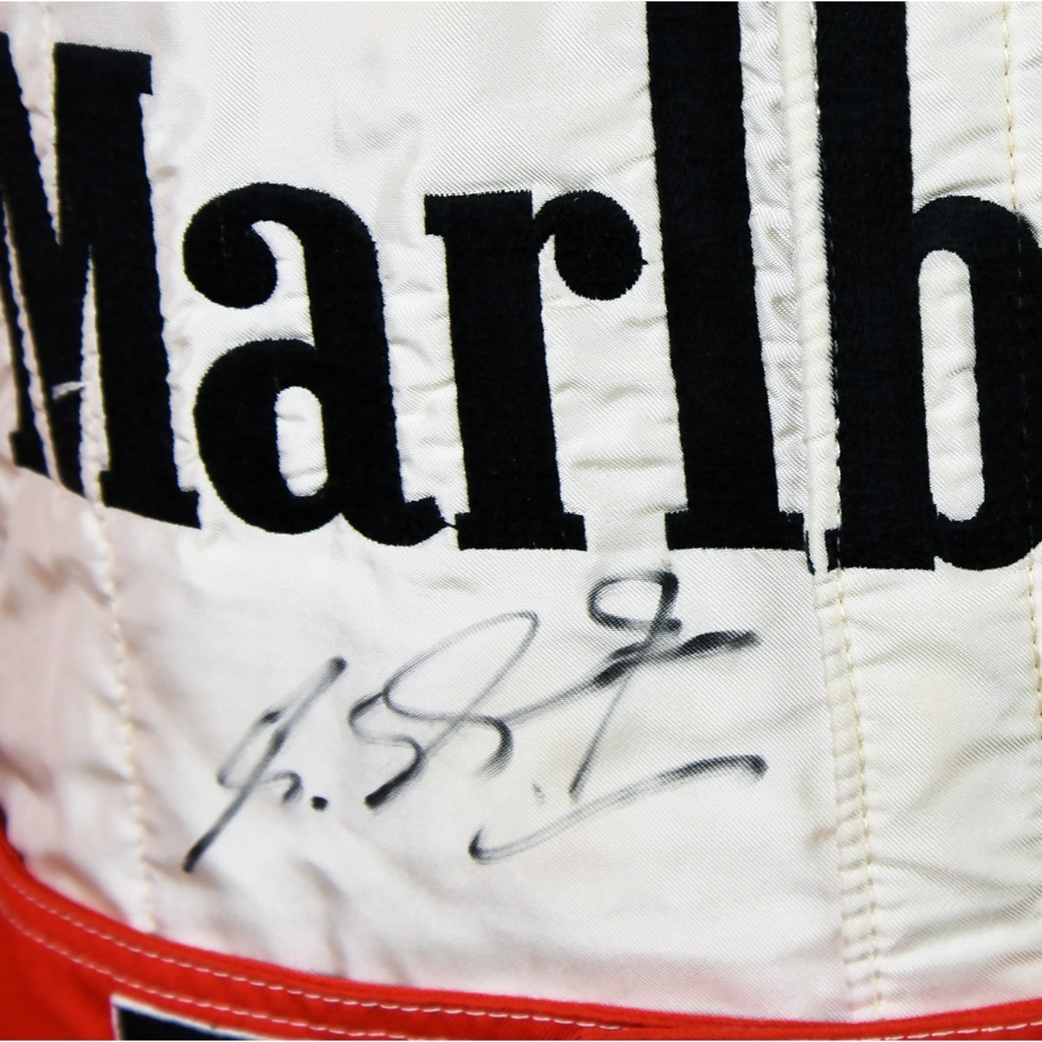Close-up of Schumacher’s 1997 F1 race suit, displaying detailed stitching and rich red fabric, with sponsor logos highlighting his drive during the 1997 season.