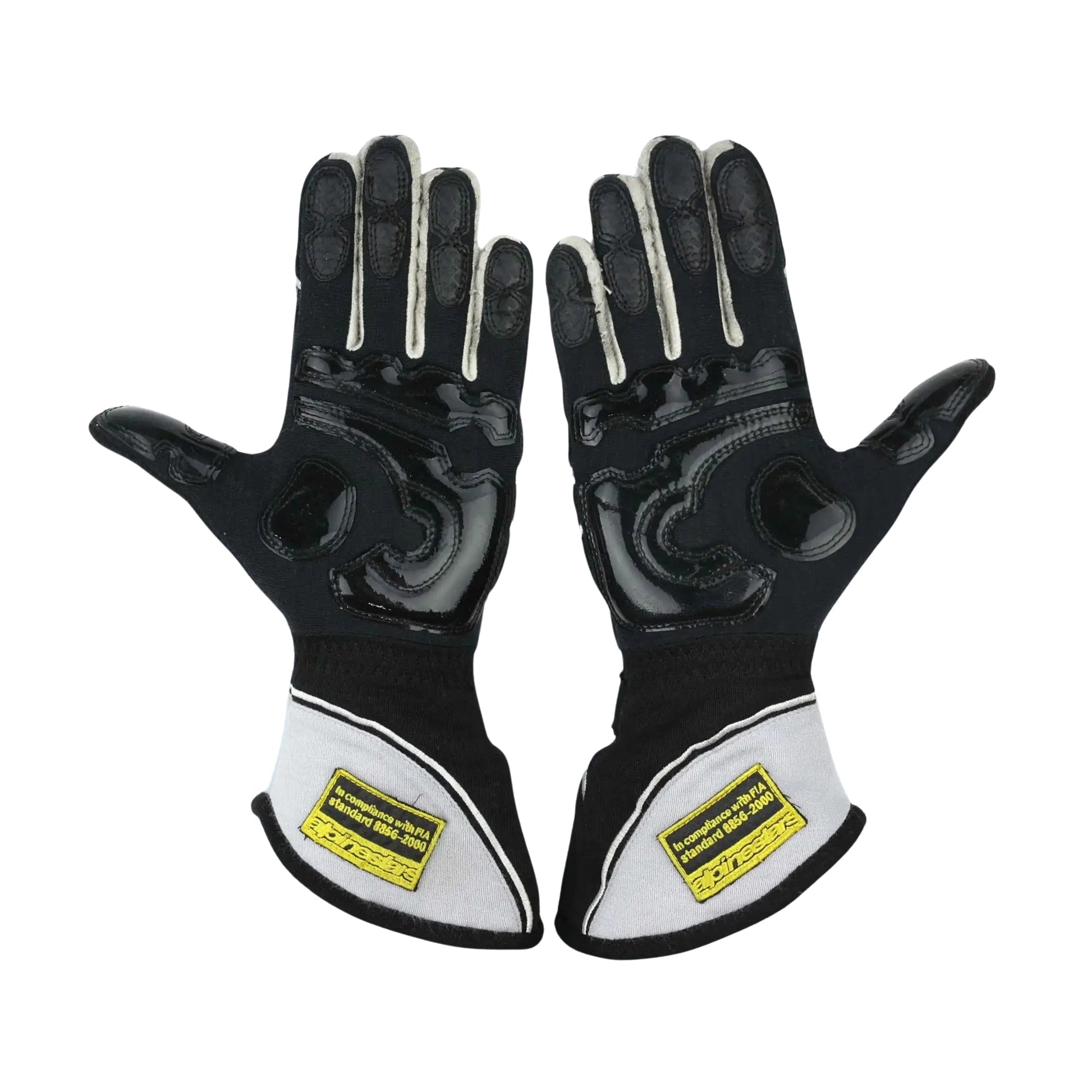 Pair of black and white Jenson Button 2015 F1 Racing gloves with yellow labels on a white background