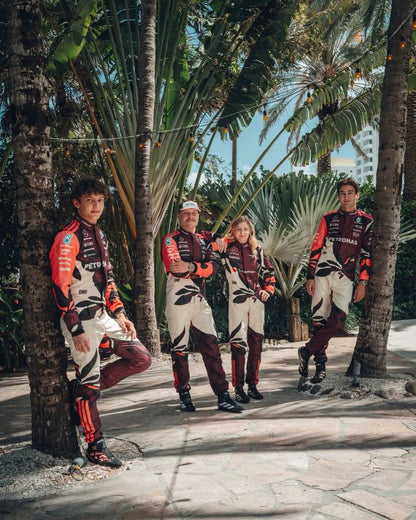 Four people in matching outfits standing among palm trees.